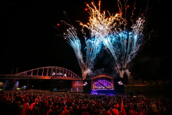 Outdoor LED-scherm hangend aan brug, met IMAG-schermen aan weerszijden van het podium.